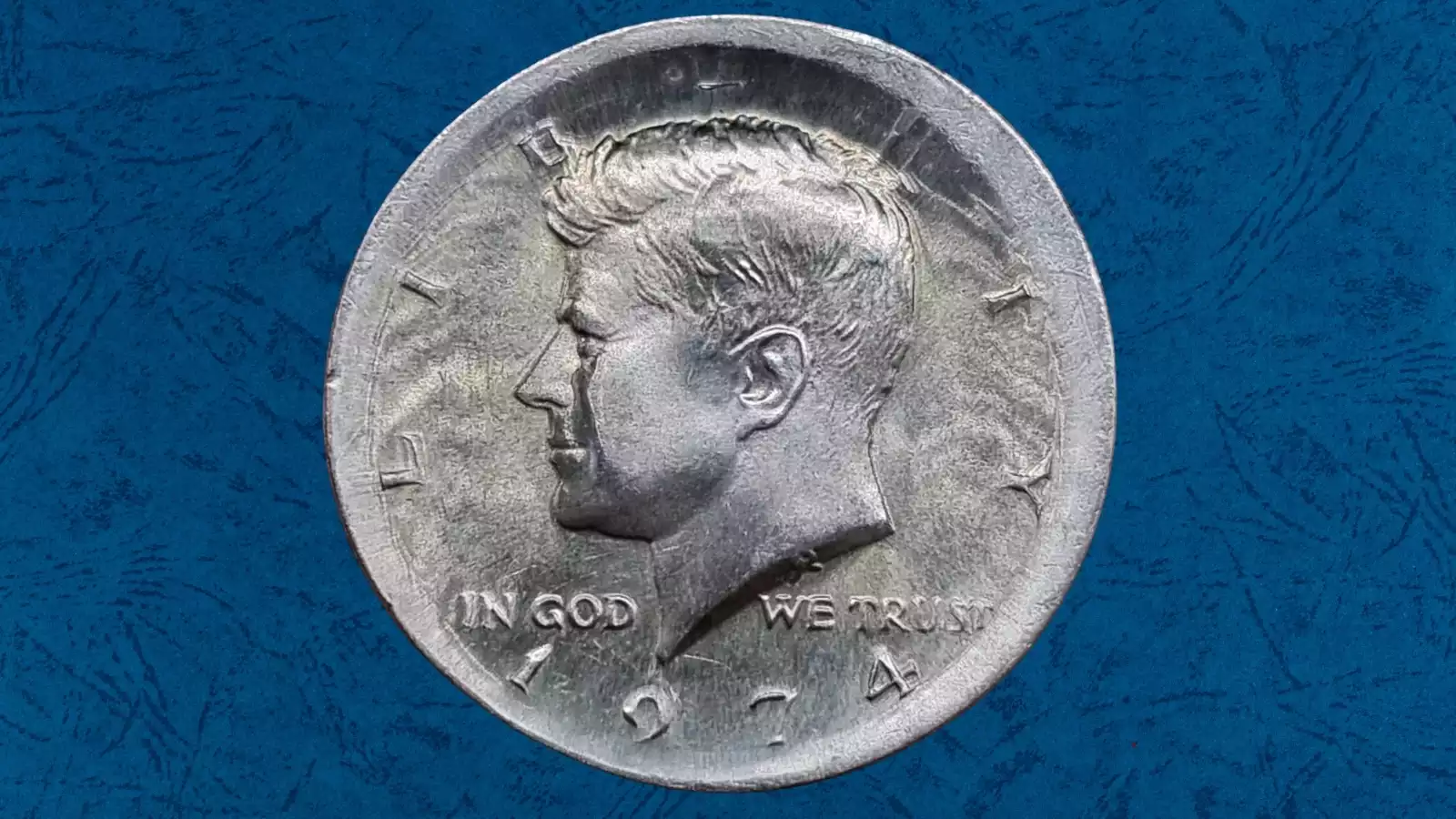1974 Kennedy Half Dollar broadstrike error — coin noticeably wider than normal with flat rim and design spread outward, compared to standard-sized coin; a mint error worth $40–$250+